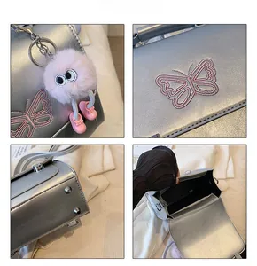 Détails du sac argenté métallisé avec broderie papillon et accessoire de charme en peluche