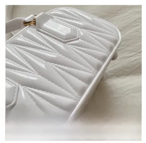 Detailed macro of white glossy jelly bag with geometric quilting and gold D-ring
