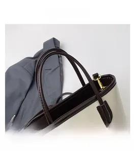 Détails du sac cabas bicolore avec poignées en cuir marron et boucles métalliques dorées