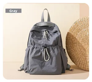 Macro view of gray nylon backpack featuring large drawstring front pocket and textured zipper pull