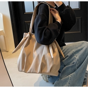 Detailed shot of beige tote bag with knot strap detail showing soft fabric texture