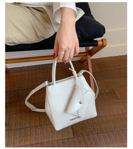 Detail of white lychee leather tote bag featuring a small envelope pouch and metal logo