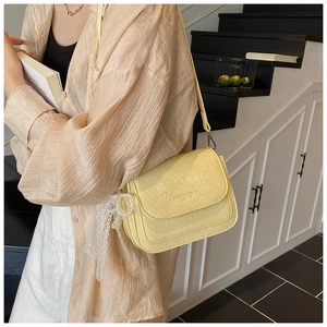 Sac bandoulière en cuir froissé jaune pâle porté par un mannequin dans un intérieur chic