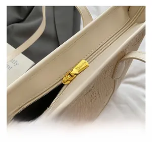 Detail hochwertiger goldener Reißverschluss an beiger geprägter Tragetasche für Damen