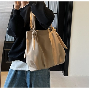 Detail of the oversized decorative shoulder knot on khaki tote bag for casual chic style