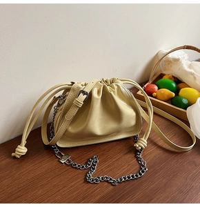 Detail of light yellow cloud bag with pleated texture and silver chain strap