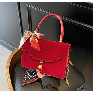 Detail of red velvet bridal handbag with silk scarf decor and gold metal chain strap