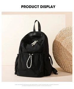 Detail view of black lightweight nylon backpack with drawstring and top ribbon handle