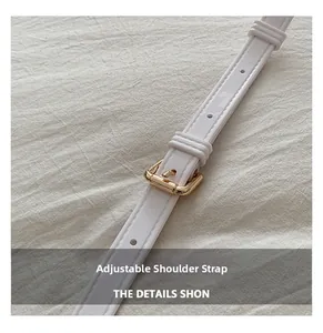 Close-up of adjustable white faux leather strap with golden metal buckle on fabric