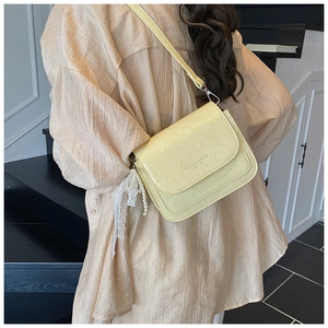 Détail du sac bandoulière jaune clair avec texture plissée et breloque en perles