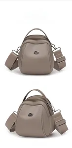 Close-up of khaki shell bag showing triple zipper compartments and wide strap details