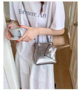 Detail of silver metallic crossbody bag with ruffled texture and hanging coin purse