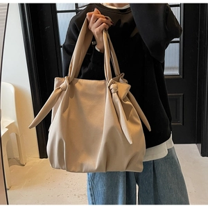 Detail of knot handle and pleated texture on a large beige minimalist tote bag