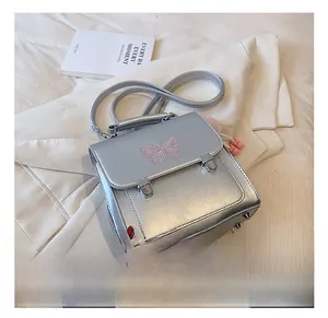 Détail du sac à dos argenté avec broderie papillon rose et pendentifs décoratifs