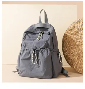 Detail view of water-resistant gray nylon backpack with drawstring pockets and woven cords