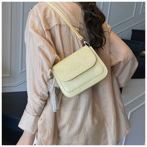 Vue détaillée du sac bandoulière crème en cuir crocodile avec pendentif en perle et dentelle