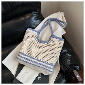 Close-up of cream and blue hollow crochet tote bag on black leather chair with white blazer