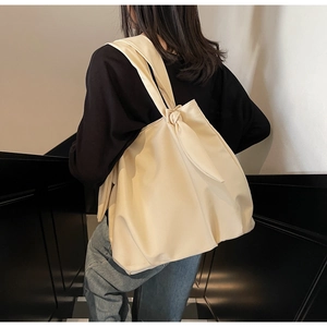 Detail view of beige canvas tote bag featuring stylish knotted shoulder strap design