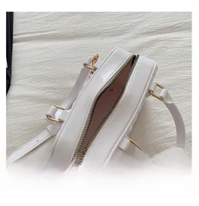 Top view of white quilted handbag showing pink interior and gold zipper details