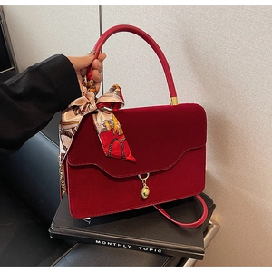 Detail of red velvet handbag with vintage gold clasp and decorative printed silk scarf