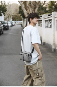 Detail of grey multi-pocket nylon messenger bag showing a crossbody fit with casual attire