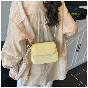 Détail d'un petit sac bandoulière crème avec breloque en perles et fermoir argenté