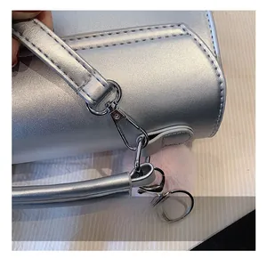Détail d'un sac argenté avec crochets métalliques et pendentif en peluche rose