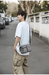 Detail view of grey nylon crossbody bag with dual front pockets and adjustable strap