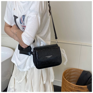 Détail du sac à bandoulière noir avec texture vintage et breloque en dentelle perlée