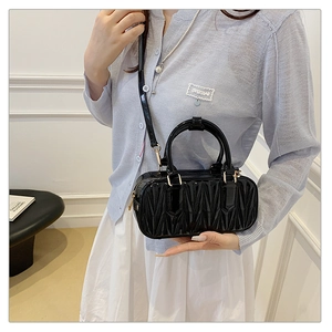 Detail of black quilted leather crossbody bag with gold hardware and top handle design