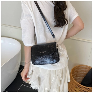 Vue détaillée d'un sac bandoulière noir brillant avec lettrage argenté sur modèle