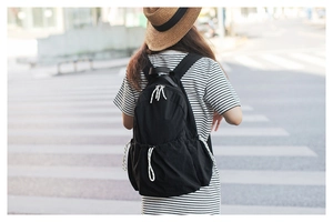 Street view of a person wearing the minimalist black nylon backpack with striped zipper pulls