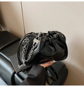 Detail der schwarzen Lackleder-Eimertasche mit silberner Kette und quadratischem Schloss
