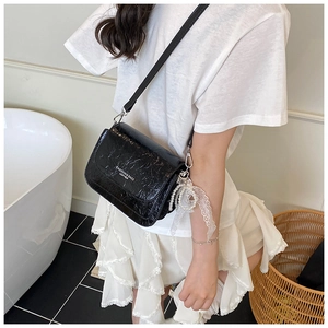 Détail du sac bandoulière en cuir froissé noir avec pendentif en perles et dentelle