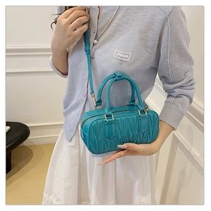 Detail of tiffany blue quilted barrel bag with gold hardware and adjustable strap