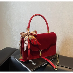 Macro shot of dark red velvet bridal handbag with round handle and printed silk scarf detail