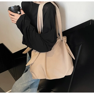 Close-up of beige tote bag featuring soft pleated leather and side knot detail design