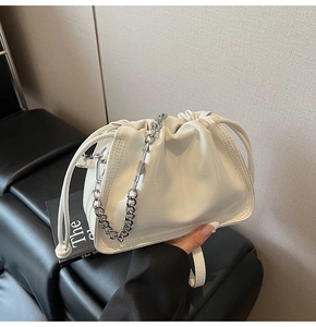Detail der cremeweißen Beuteltasche mit silberner Kette und Tunnelzug-Verschluss