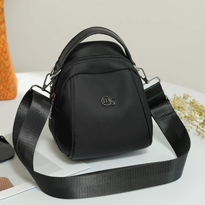 Detail of a black nylon shell bag with metal MS logo and adjustable wide shoulder strap
