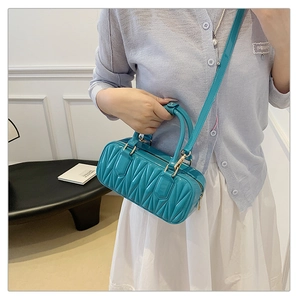 Detail showing aqua blue wave-quilted glossy finish and sleek gold hardware on handbag