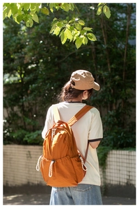 Close-up of orange nylon backpack with drawstring detail in outdoor setting