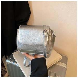 Détail d'un sac bandoulière argenté métallisé avec texture froissée et sangle réglable