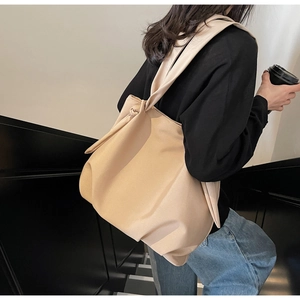 Detail view of apricot tote bag with knot shoulder strap on model in urban setting