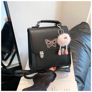 Détail du sac à dos noir avec broderie papillon rose et breloque peluche monstre