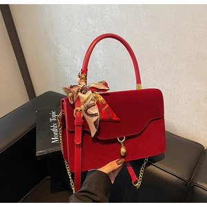 Detail of red velvet bridal handbag with silk scarf handle and elegant gold chain strap