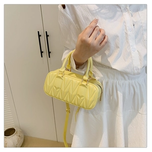 Detail of yellow quilted leather mini bag with gold-tone hardware and top handle