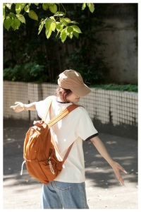 Outdoor shot of an orange nylon backpack with drawstring pocket and large capacity