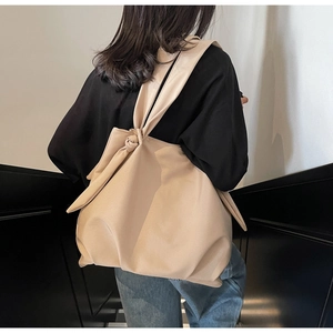 Detail of minimalist beige PU leather tote bag featuring a unique knotted shoulder strap