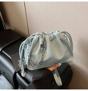 Detailed macro view of the light blue patent leather finish and silver chain on the bucket bag