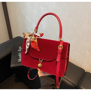 Detail of red velvet bridal handbag with golden orb pendant and floral silk scarf